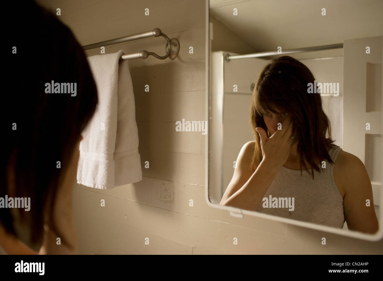 Woman looking in bathroom mirror Stock Photo