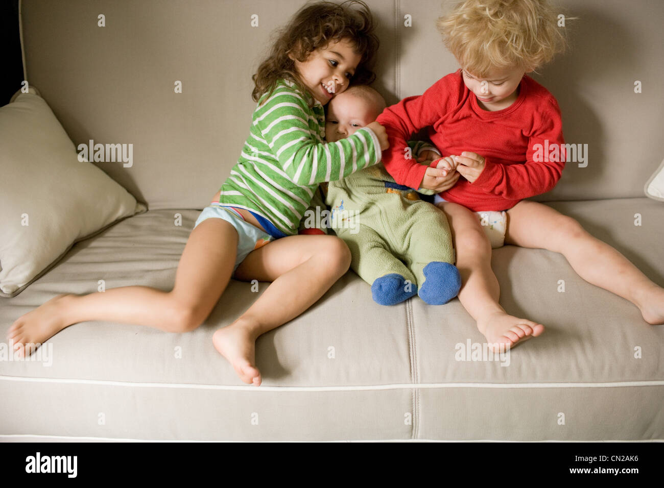 Three siblings sitting on sofa Stock Photo