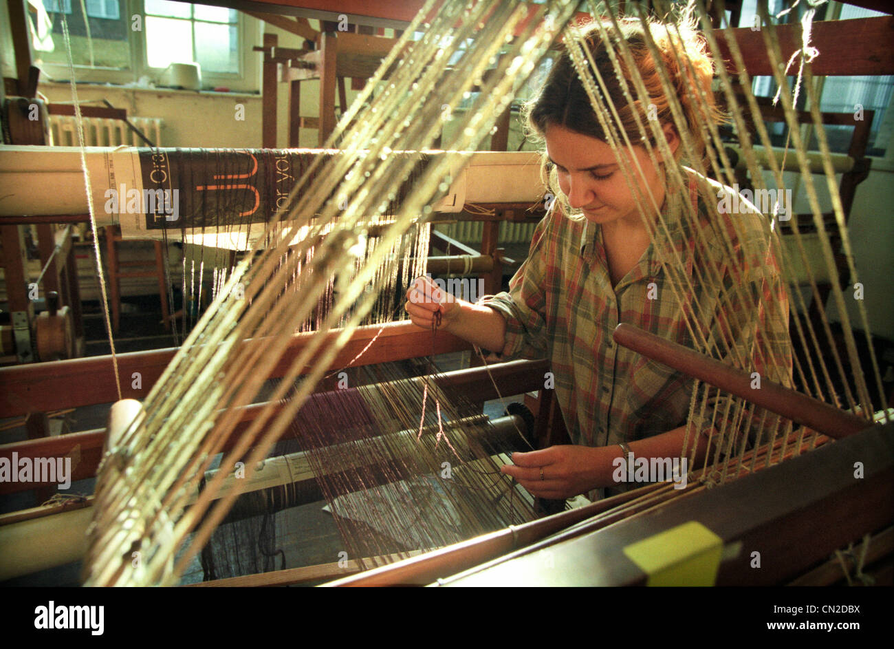 A University of Brighton textile student inspects the wool threads on a loom as part of her degree course. Stock Photo