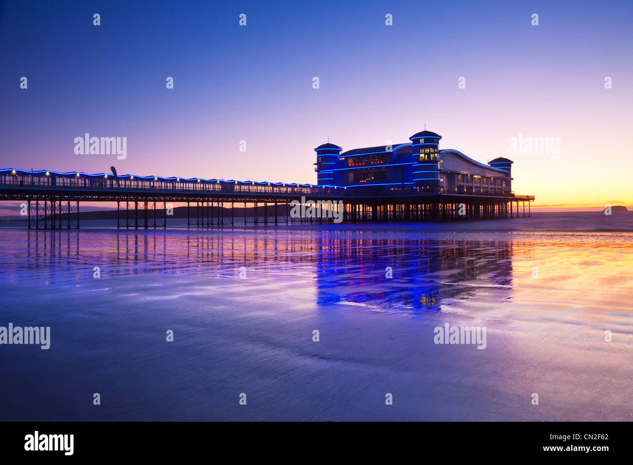 Twilight over the Grand Pier at Weston-Super-Mare, Somerset, England, UK reflected in the wet sand of the beach at high tide. Stock Photo