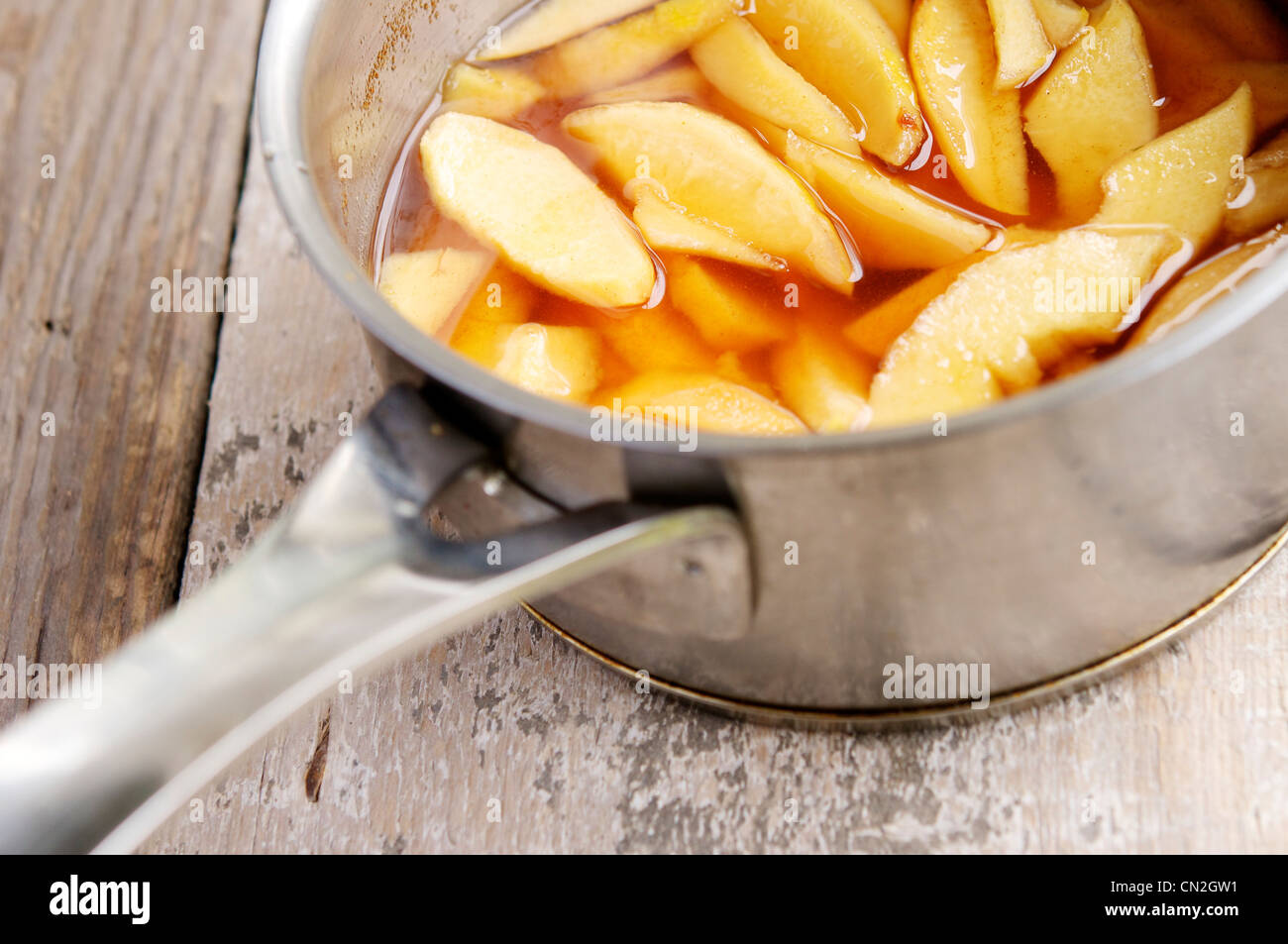 Quince pieces poaching in a syrup mixture in a medium sauce pan. Stock Photo