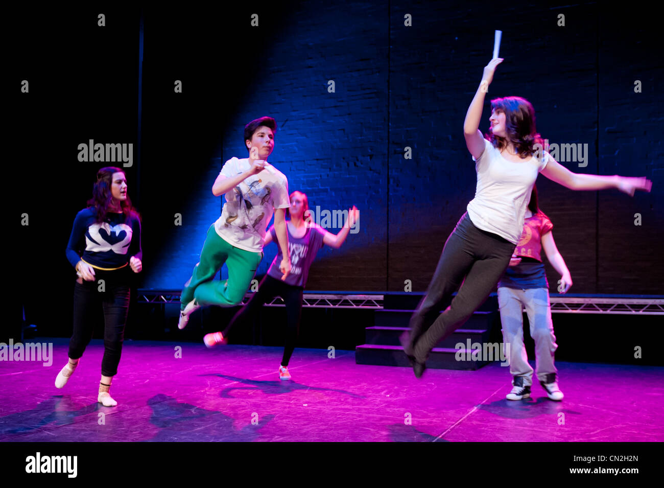 A group of boys and girls, teenagers singing and dancing in a amateur musical theatre performance production in a theatre. UK Stock Photo