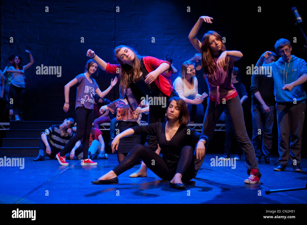 A group of boys and girls, teenagers singing and dancing in a amateur musical theatre performance production in a theatre. UK Stock Photo