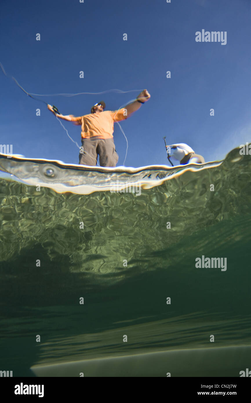 Over and Underwater View of Two Men Fly Fishing in Boat Near