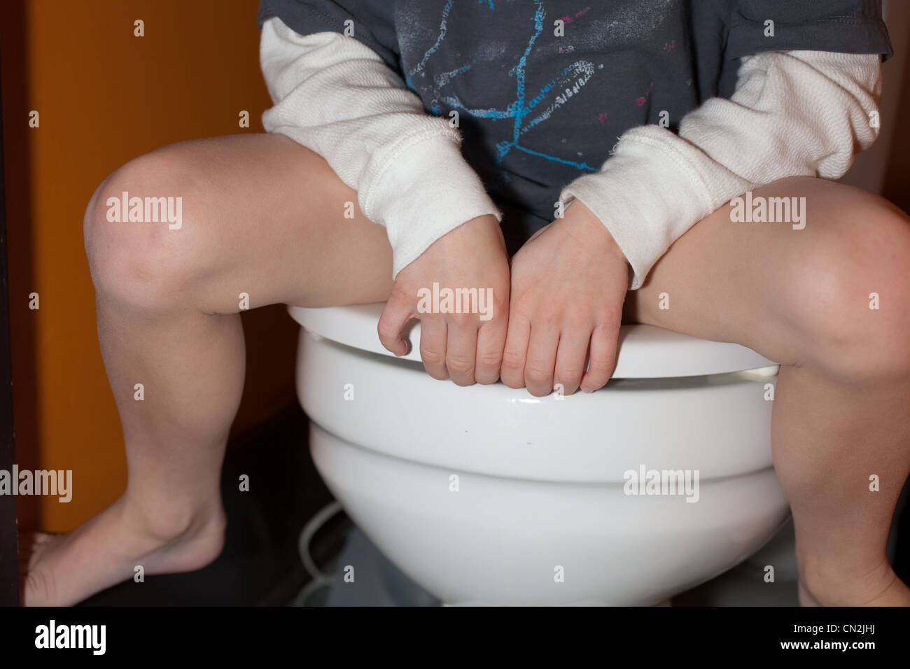 Boy sitting on toilet Stock Photo