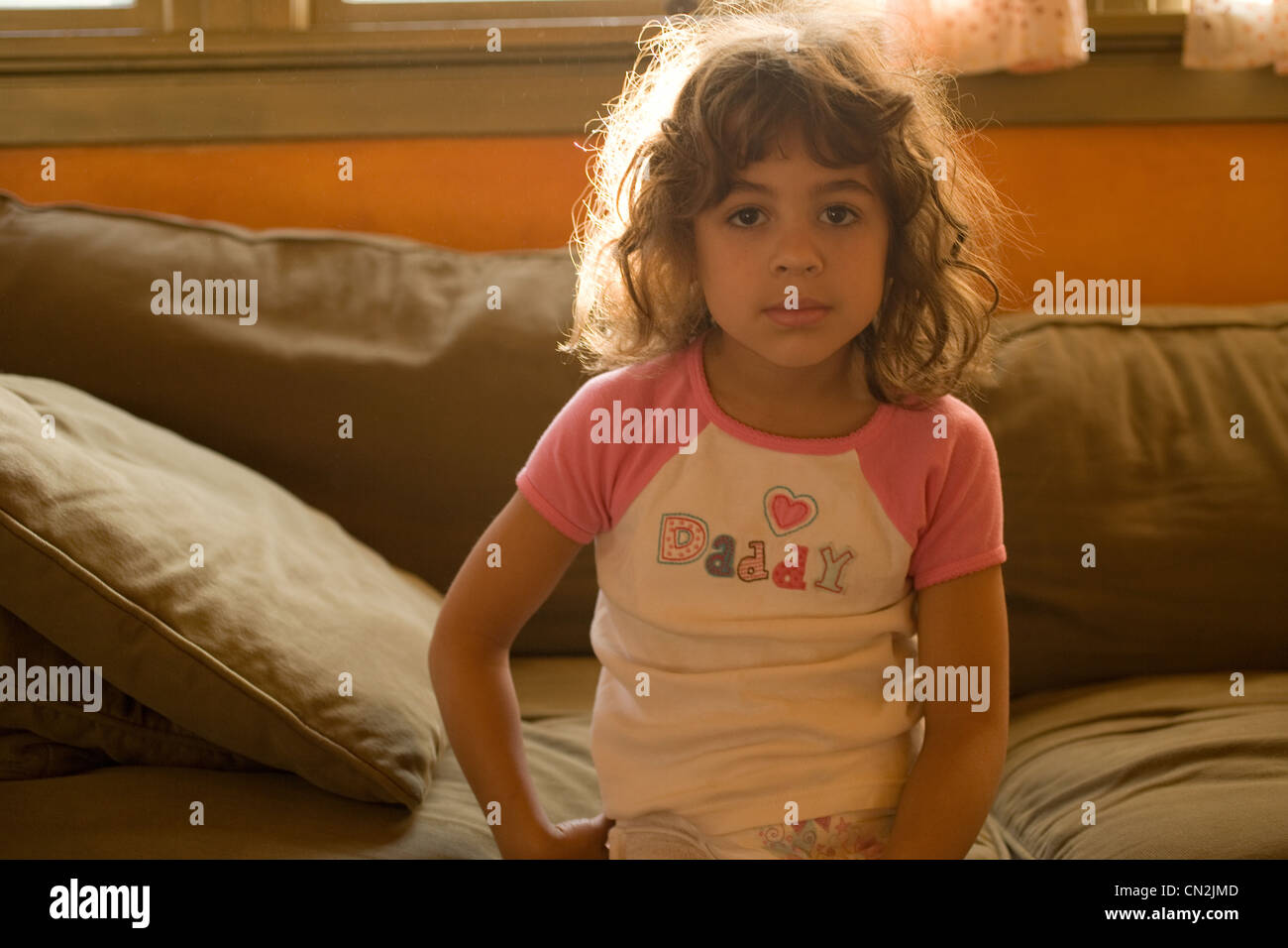 Portrait of young girl sitting on sofa Stock Photo