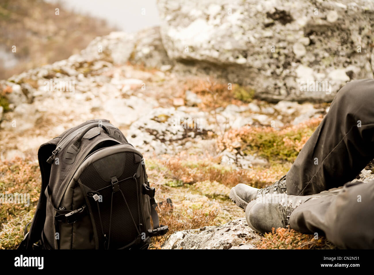 Man resting on rocks with backpack Stock Photo