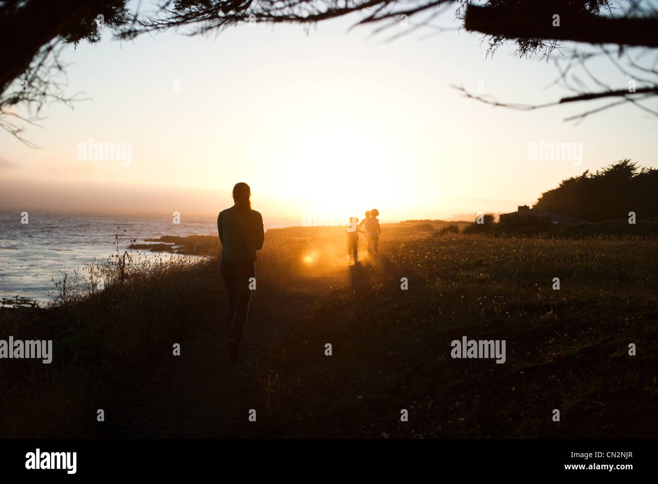 Family walking by coast at sunset Stock Photo