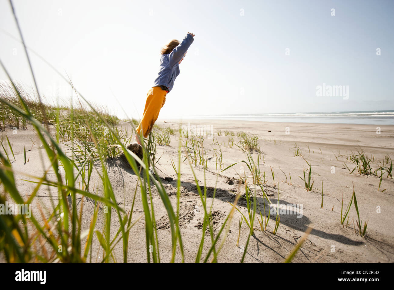 Young standing on rock on on sandy beach Stock Photo