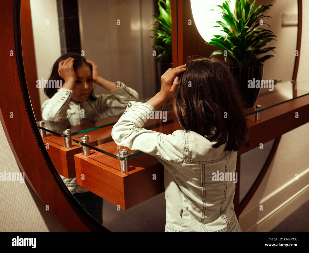 Girl looks at herself in mirror. Stock Photo