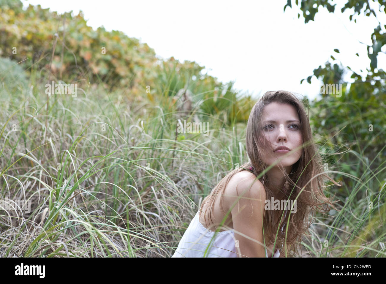 Young woman sitting in grass, looking away Stock Photo