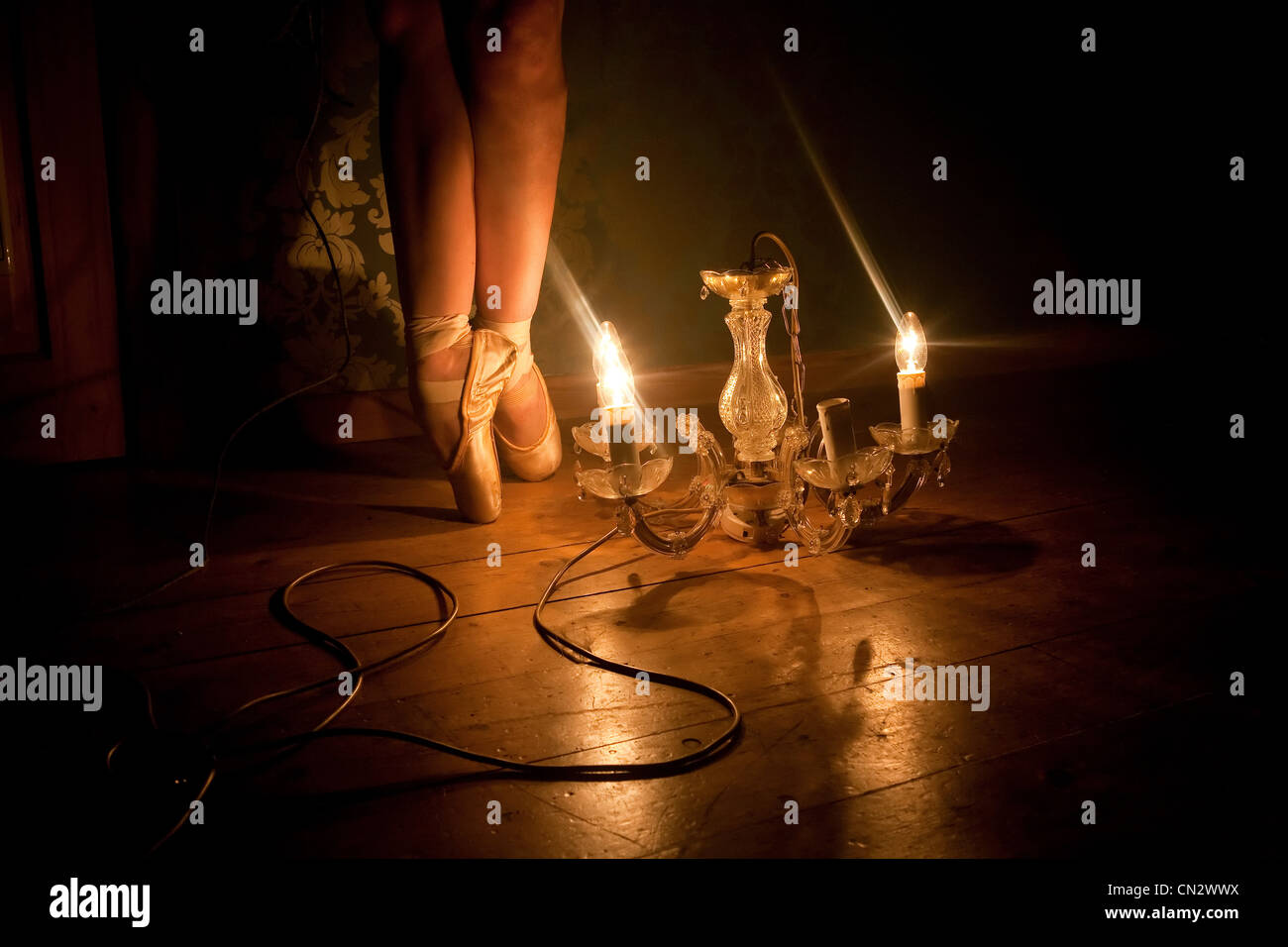 Feet of ballerina illuminated by chandelier light Stock Photo