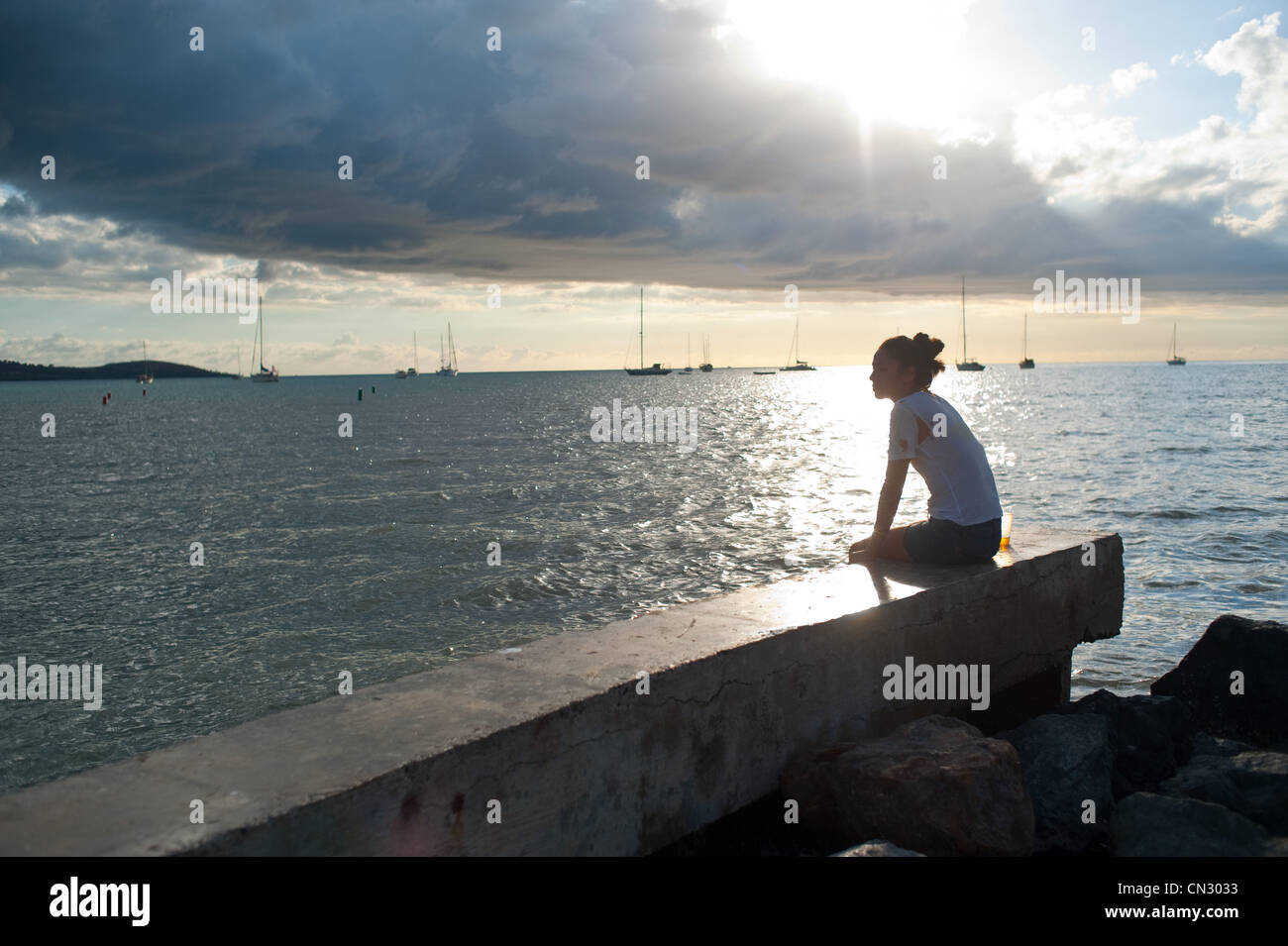 Woman sitting alone by the ocean Stock Photo