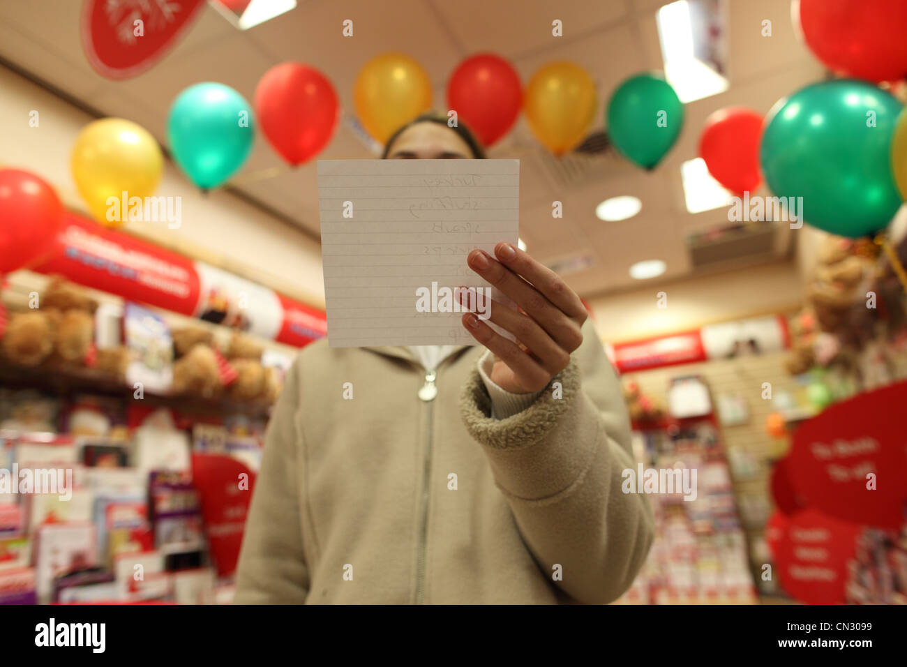 Teenage girl in shop with shopping list covering face Stock Photo Alamy