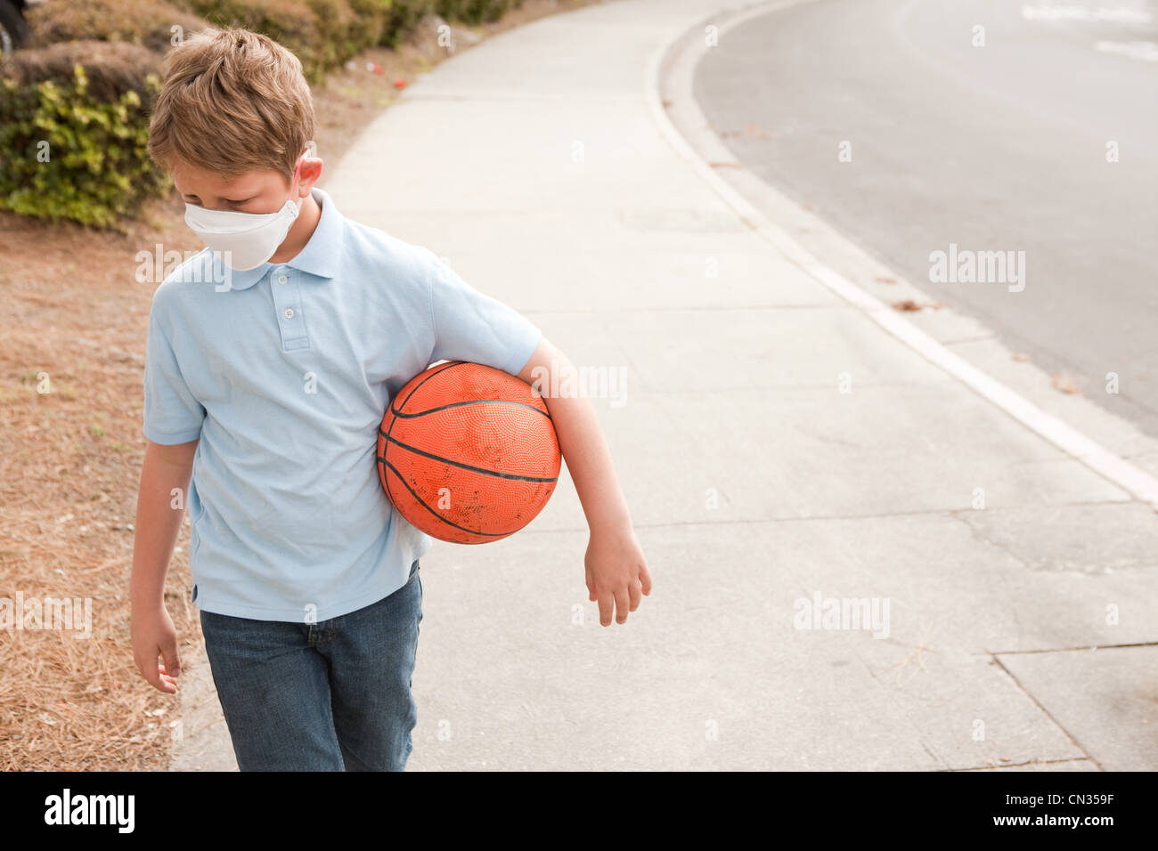 Boy wearing dust mask holding basketball Stock Photo Alamy