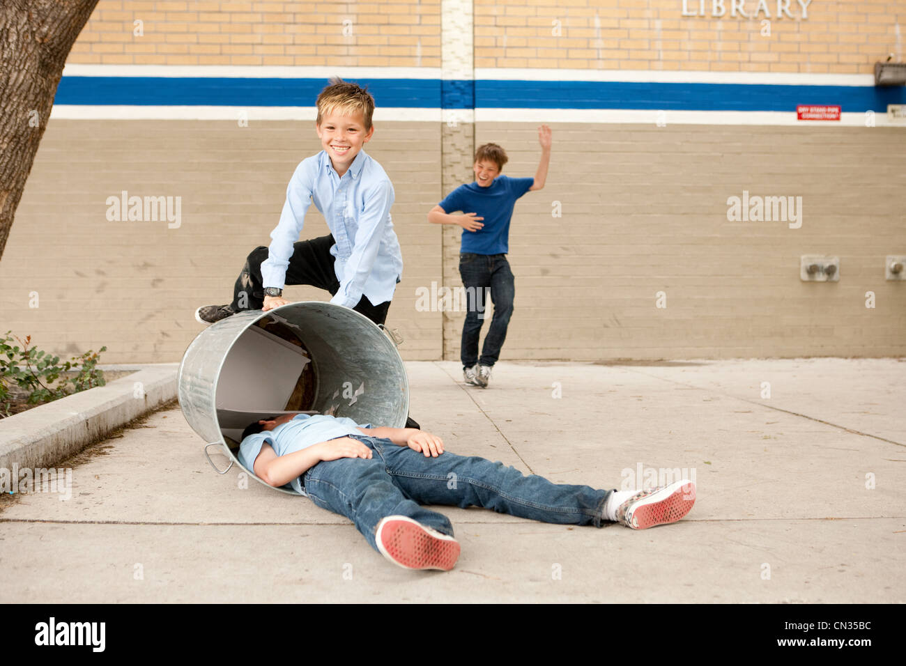 Two boys bullying another, one boy in dustbin Stock Photo