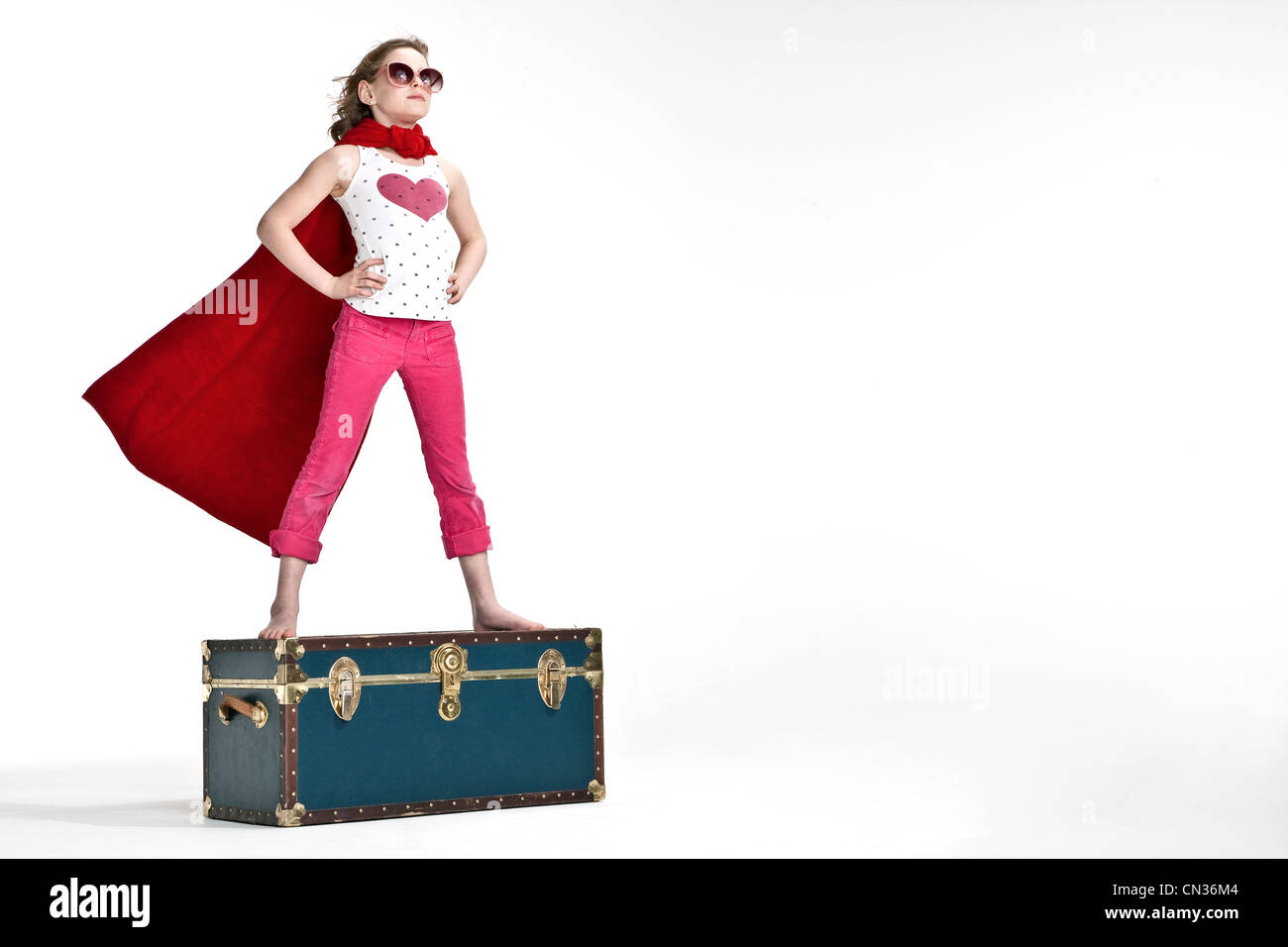 Girl standing on trunk suitcase dressed as superhero Stock Photo