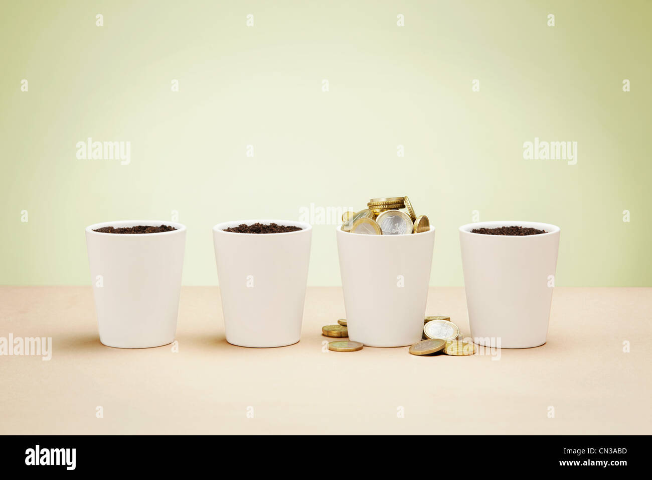 Four plant pots, one full of euro coins Stock Photo
