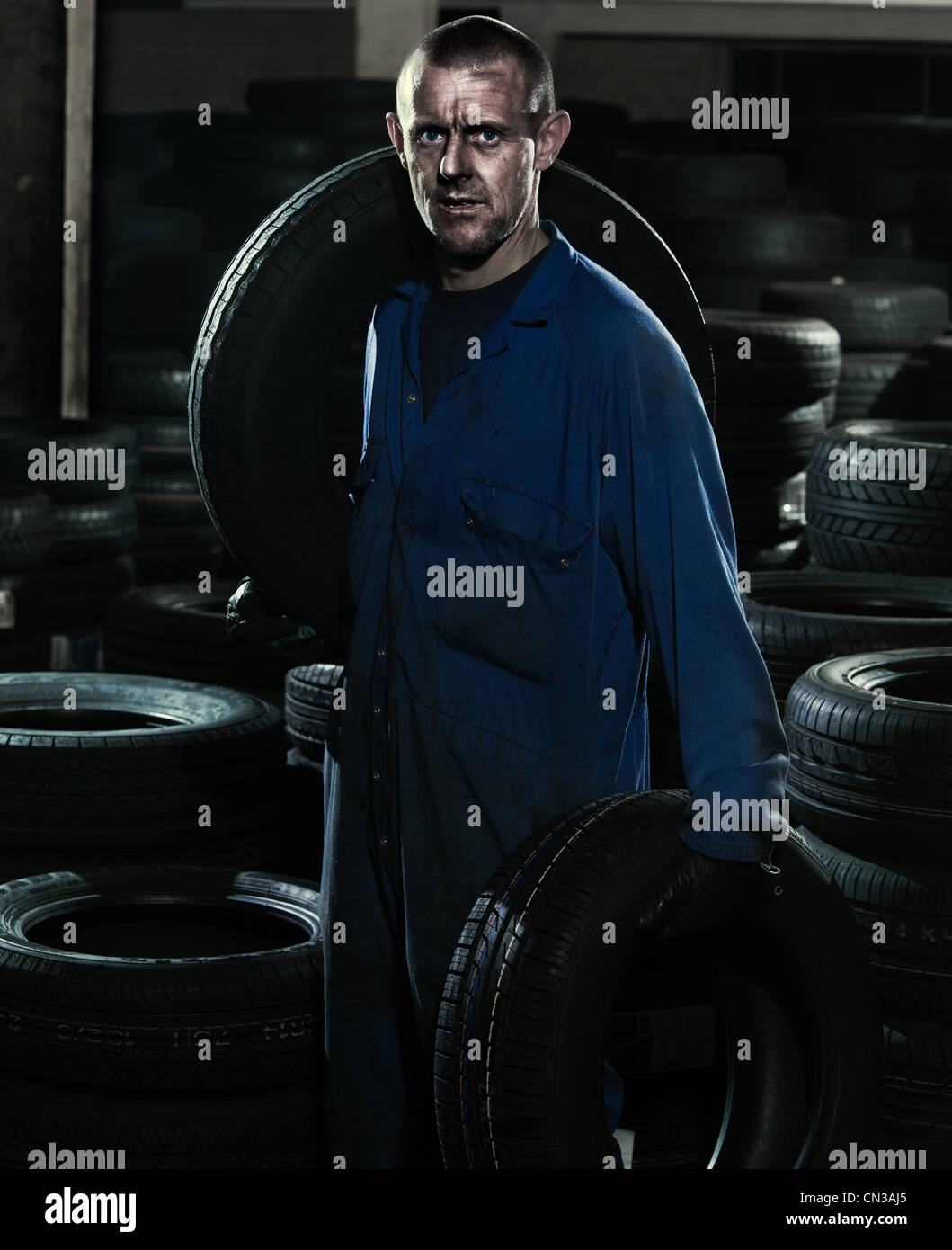 Car mechanic in workshop with car tires Stock Photo