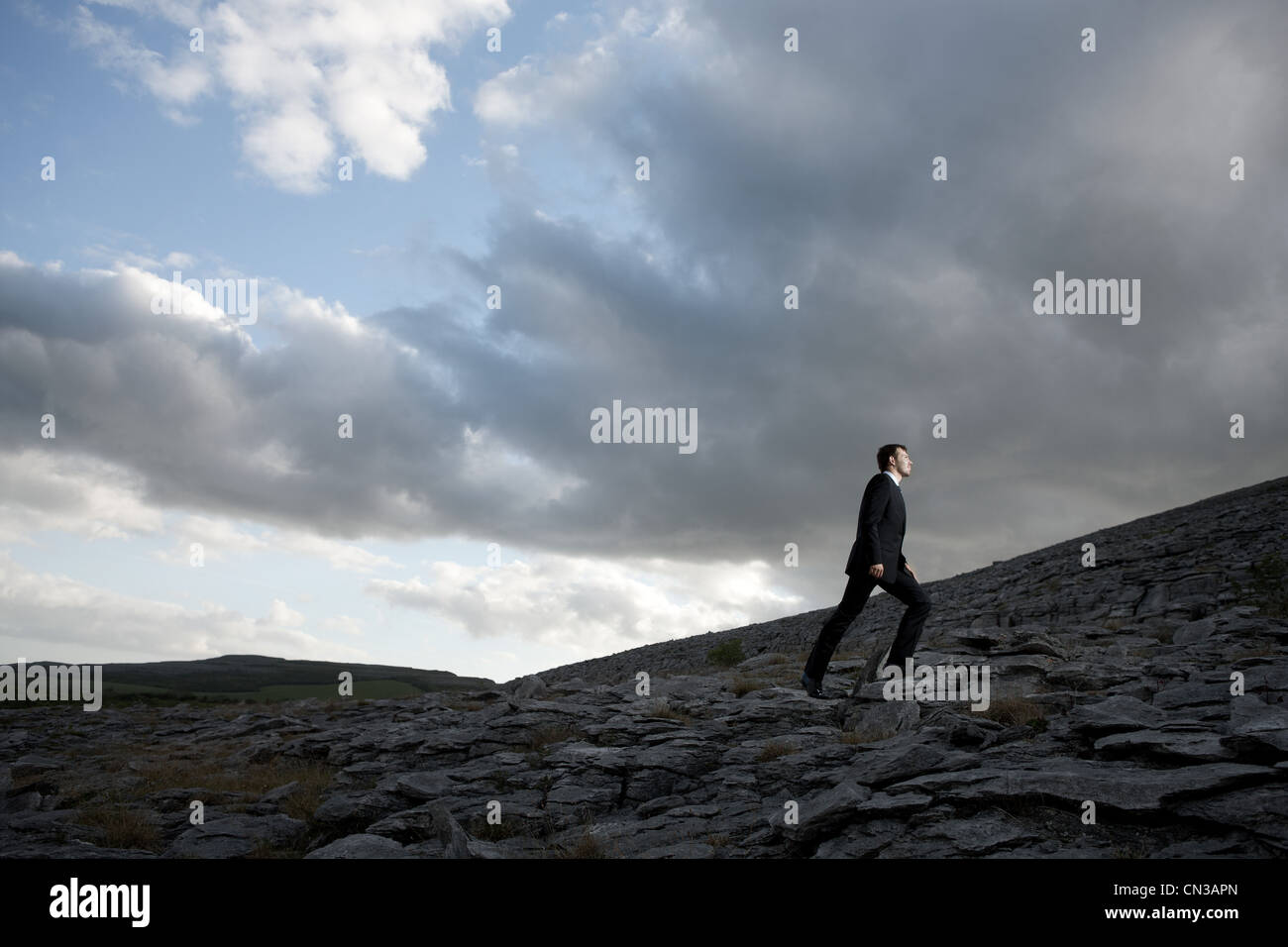 Businessman climbing rocky hill Stock Photo