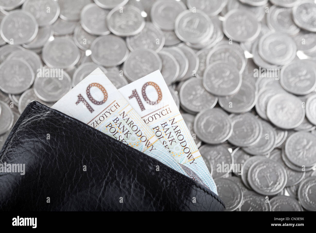Black wallet with ten polish zloty paper money laying on one polish zloty coins background. Money and savings concept. Stock Photo