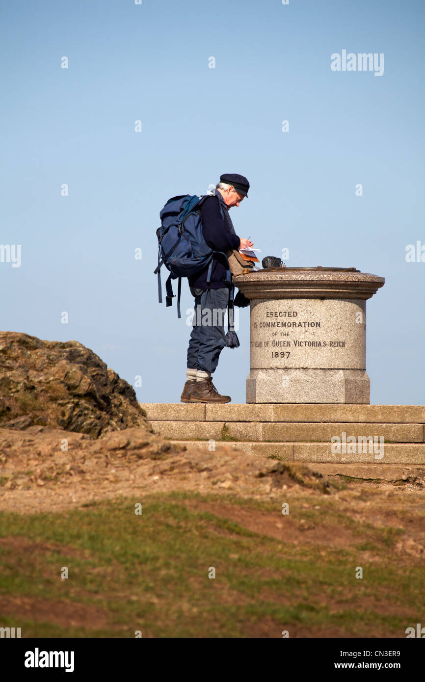 Mature man at the summit stone of the Beacon in commemoration of Queen Victoria's reign 1897 at the Malvern Hills in April Stock Photo