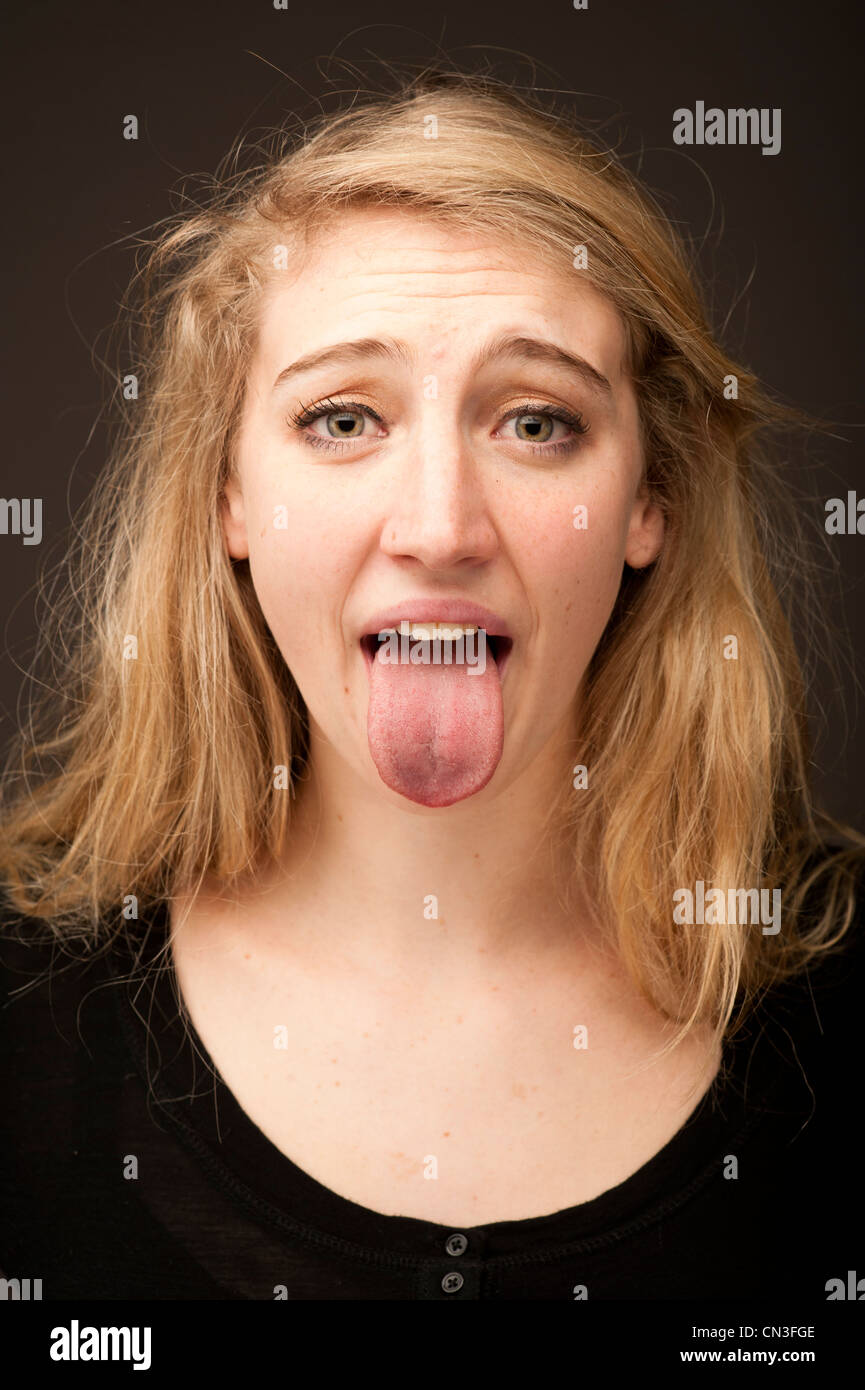 a young blonde 19 year old teenage girl sticking out her tongue looking ill sick poorly Stock Photo