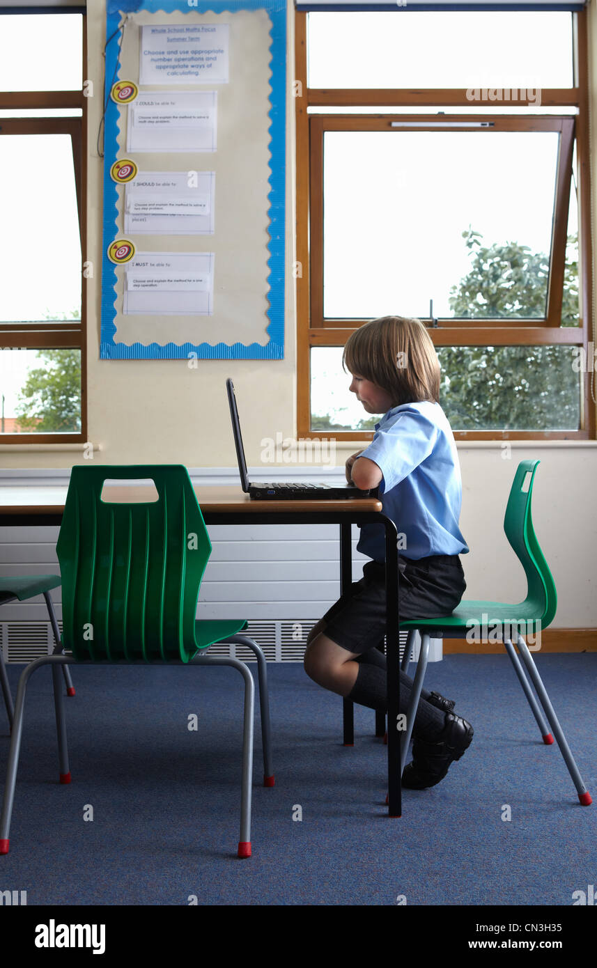School boy looking at laptop computer in classroom Stock Photo