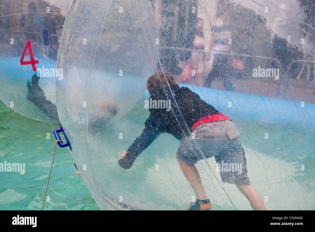 Boys playing in an inflatable 'water walker' ('hamster ball') attraction : Queen Street, Cardiff Stock Photo