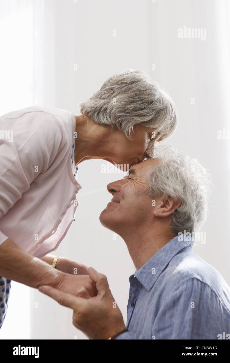 Senior woman bending to kiss man Stock Photo photo