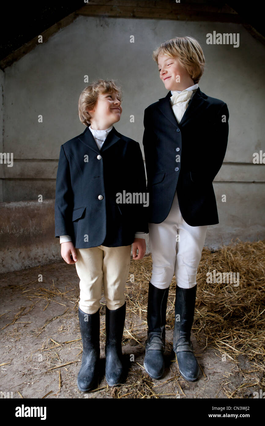 Boys wearing horse riding clothes in stable Stock Photo