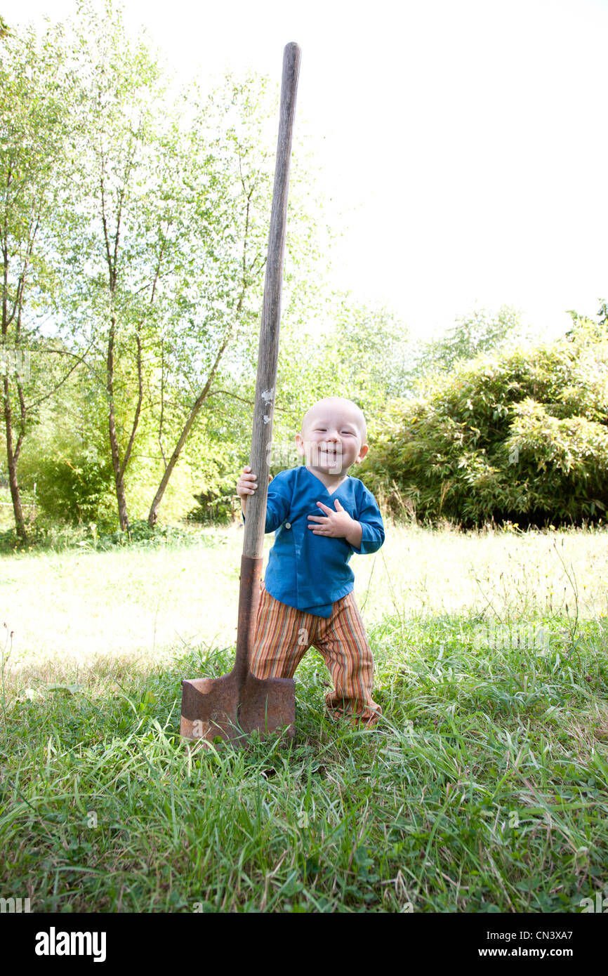 Toddler with big shovel in garden Stock Photo