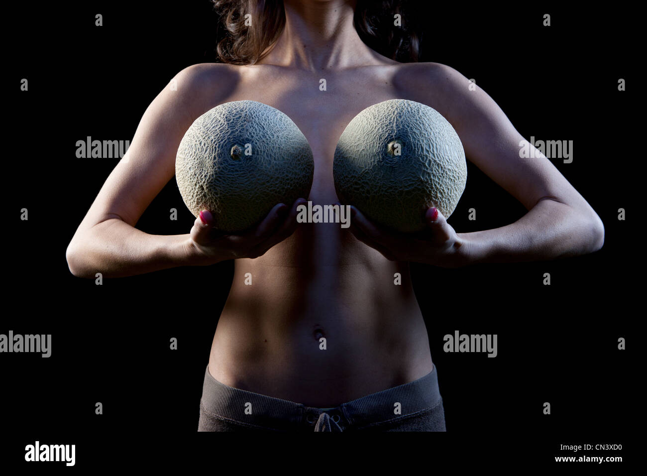 Woman holding cataloupe melons in front of breasts Stock Photo - Alamy