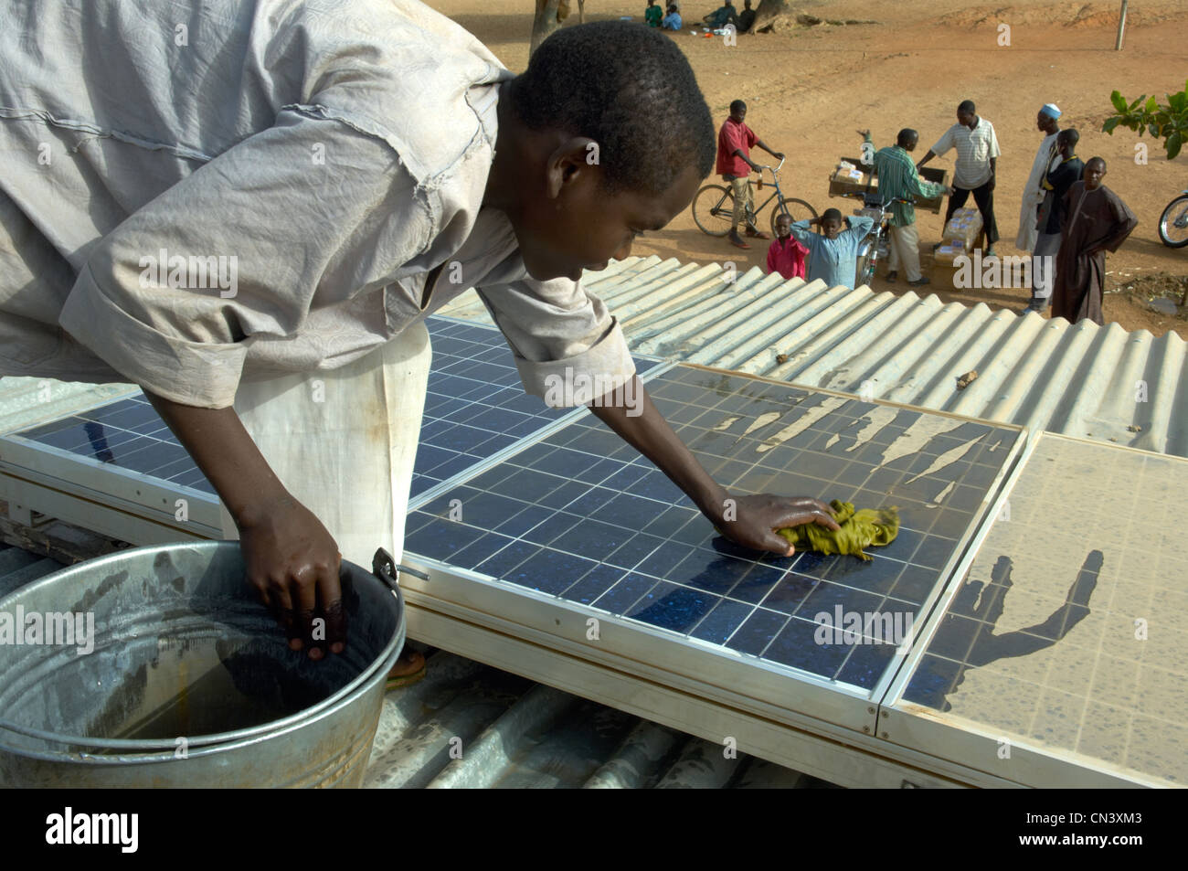 Young boy cleans dust of solar panels in Africa Stock Photo