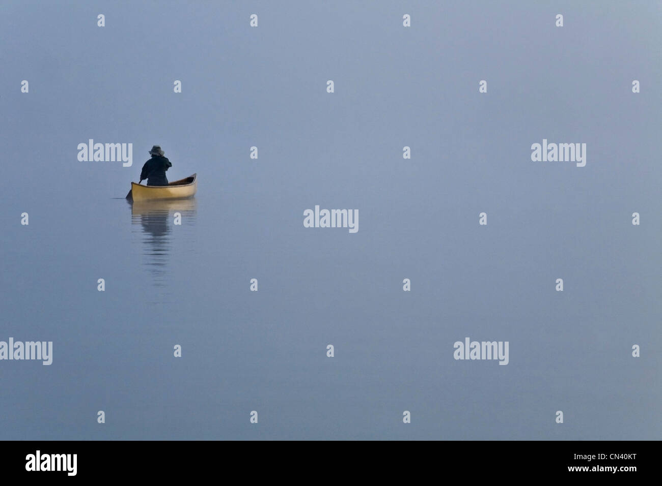 Woman paddling canoe in morning mist, Algonquin Park, Ontario Stock Photo