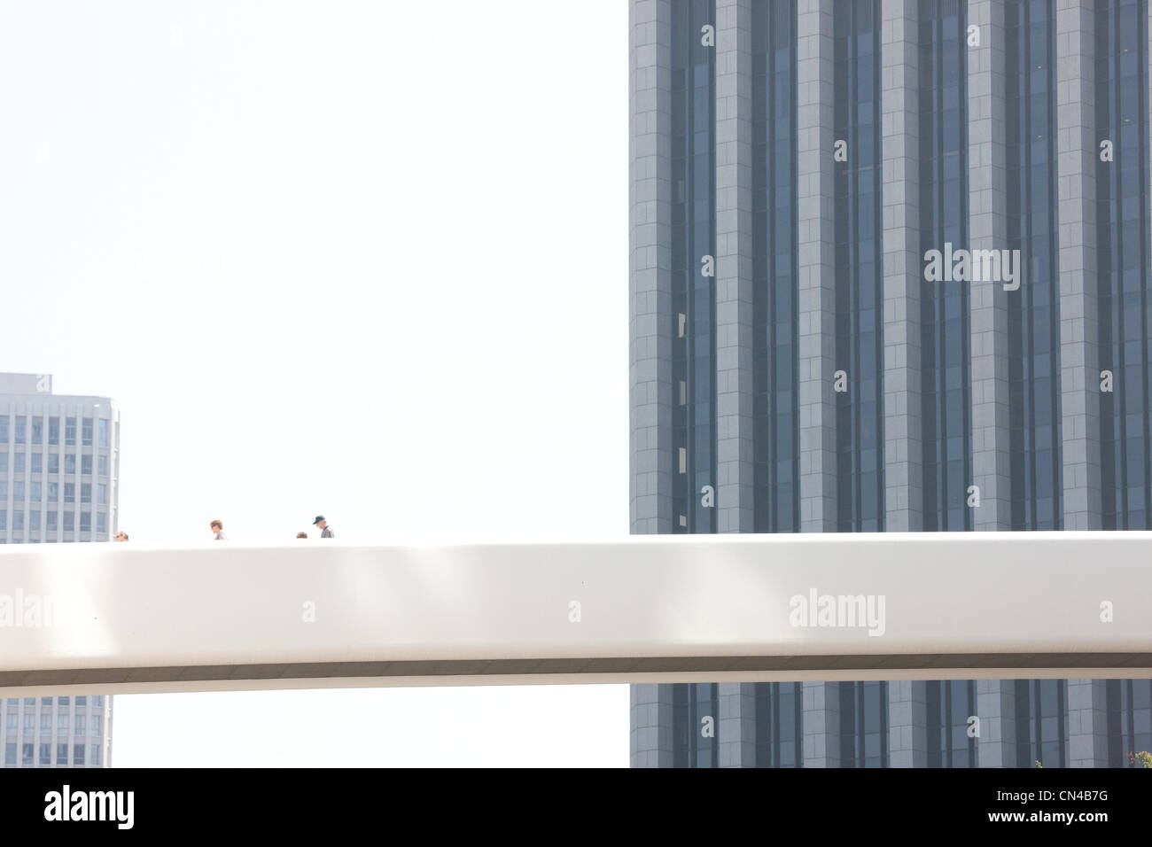 People on aerial walkway above business district Stock Photo