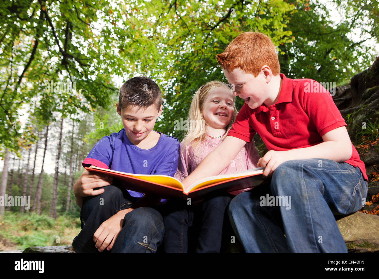 Three children looking at a book together Stock Photo