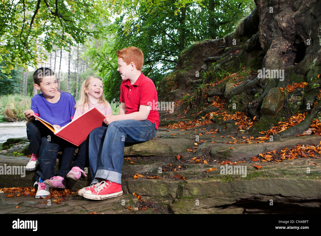 Three children enjoying a book together Stock Photo