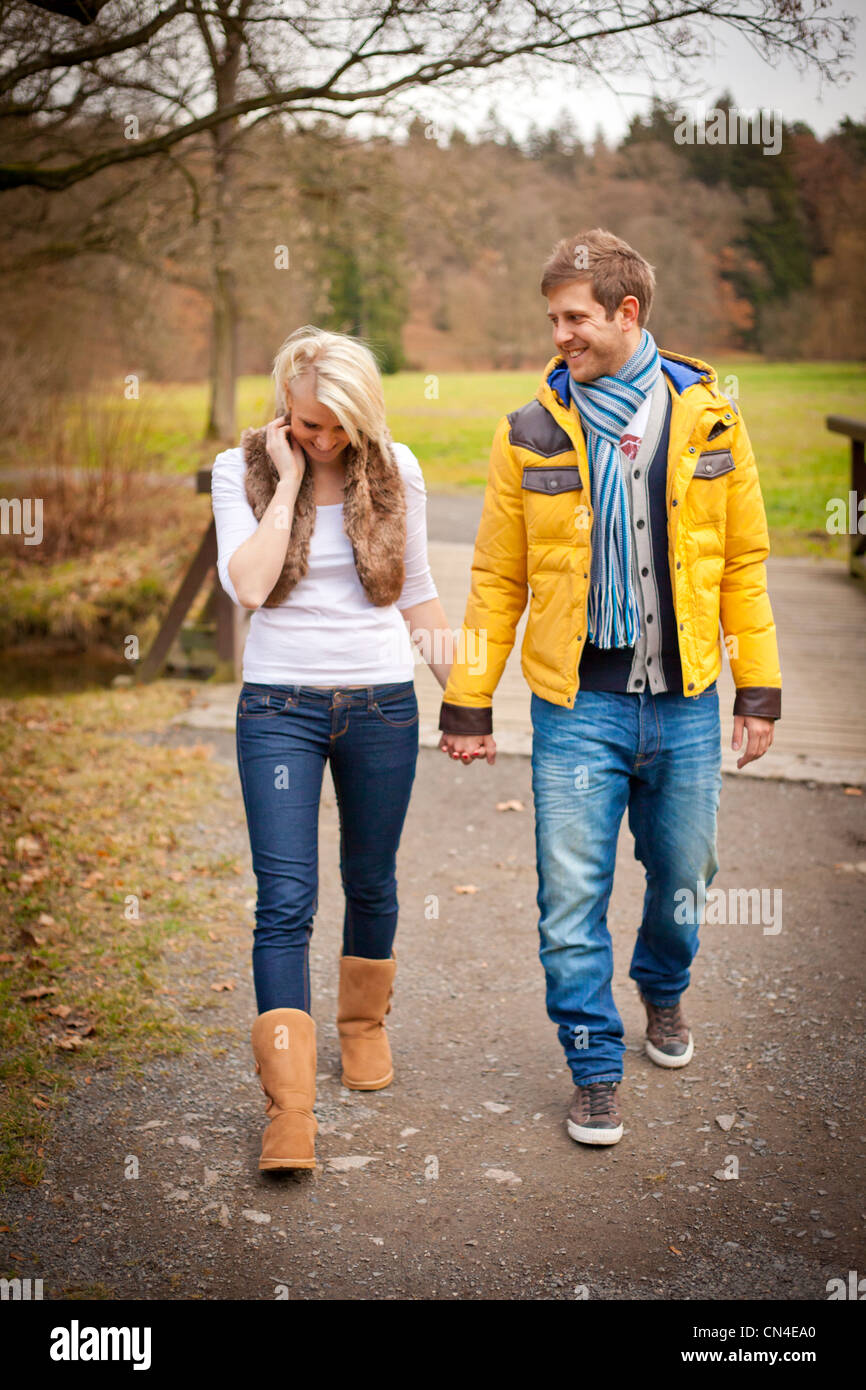 A cheerful couple walks hand in hand through a scenic park in autumn ...