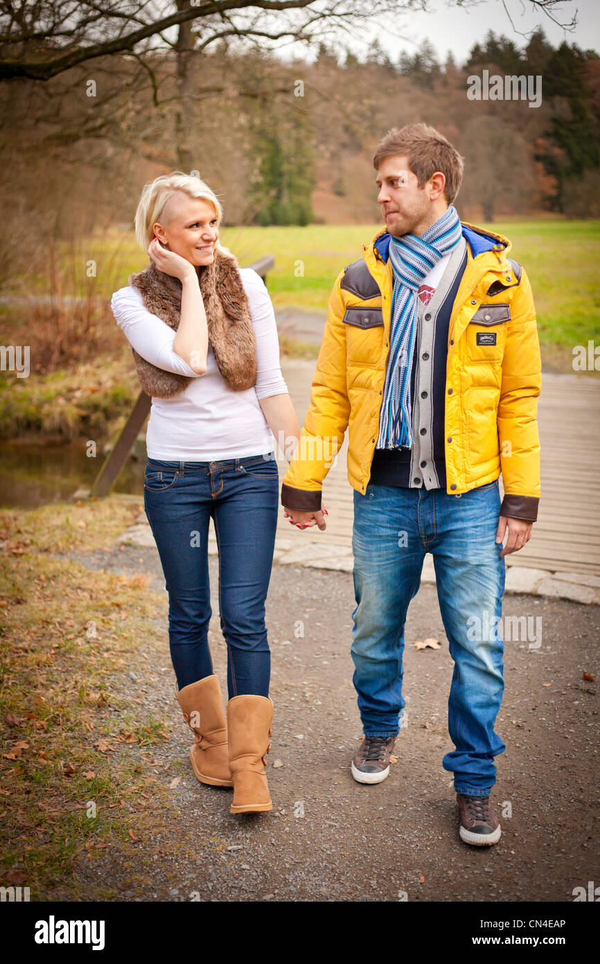 A cheerful couple walks hand in hand through a scenic park in autumn ...