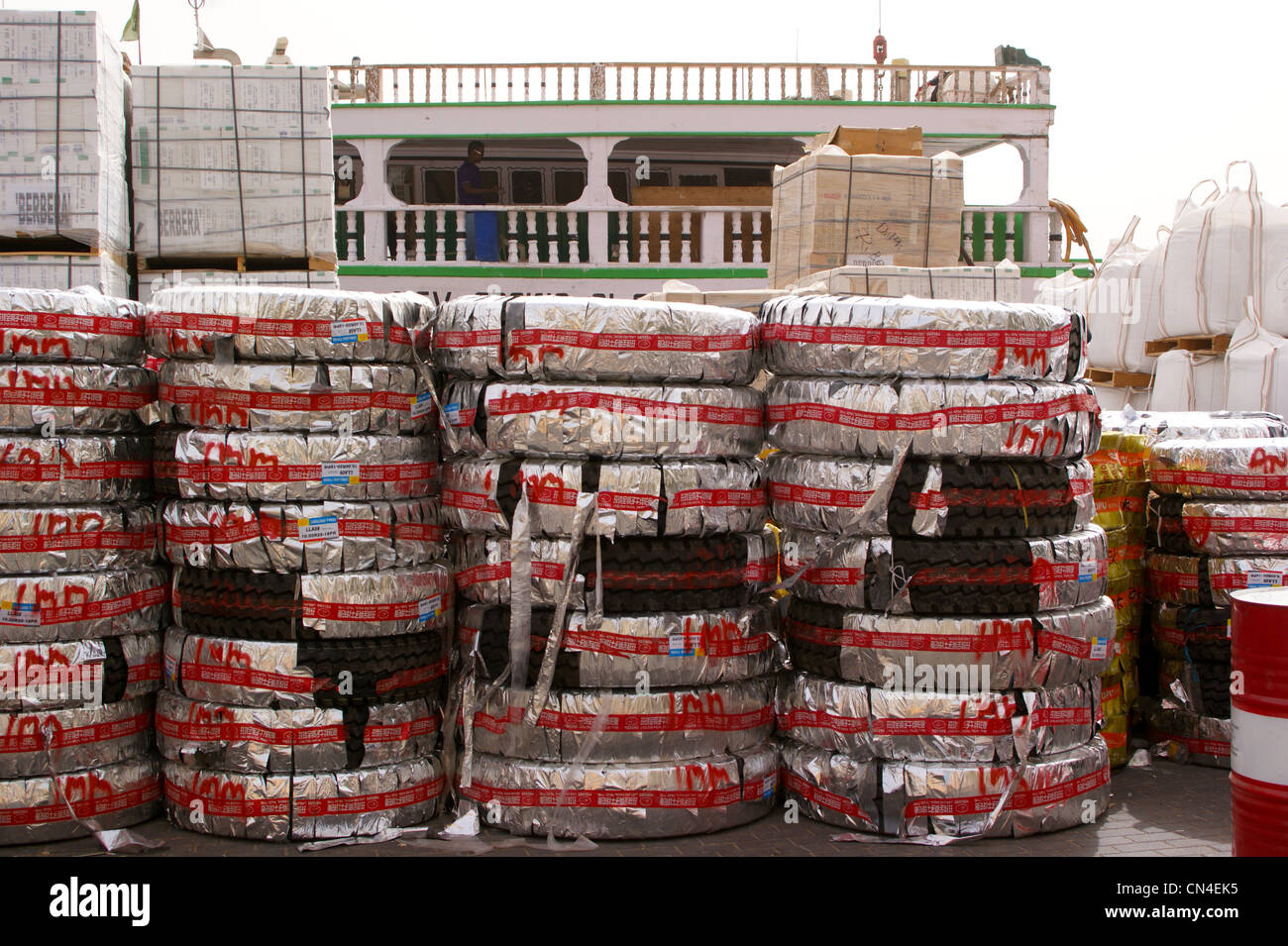 New car tyres wrapped in colourful packaging waiting to be loaded onto a dhow, Dubai Creek,  Dubai, United Arab Emirates Stock Photo