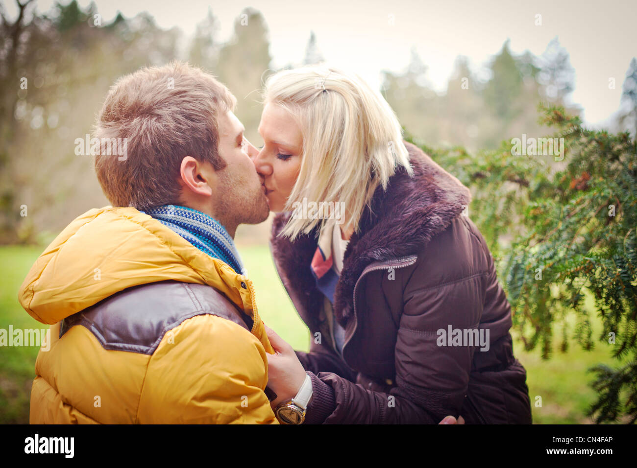 Couple kissing outside in a park Stock Photo - Alamy
