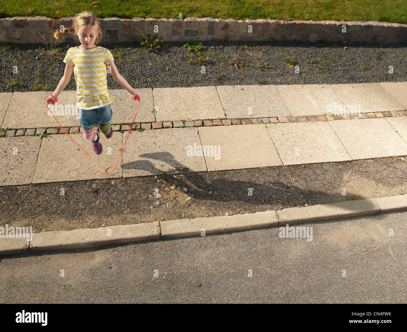 Young girl skipping on sidewalk Stock Photo Alamy