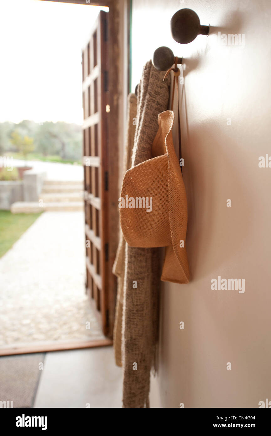 Straw hat hanging from coat rack in late afternoon sun with open door ...