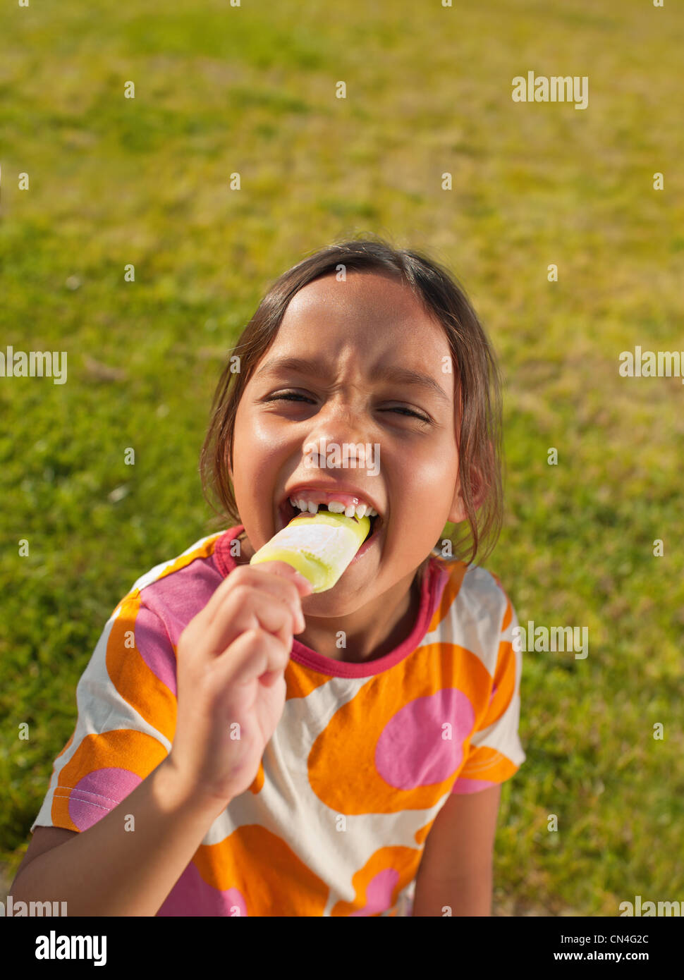 Girl biting into ice lolly, portrait Stock Photo