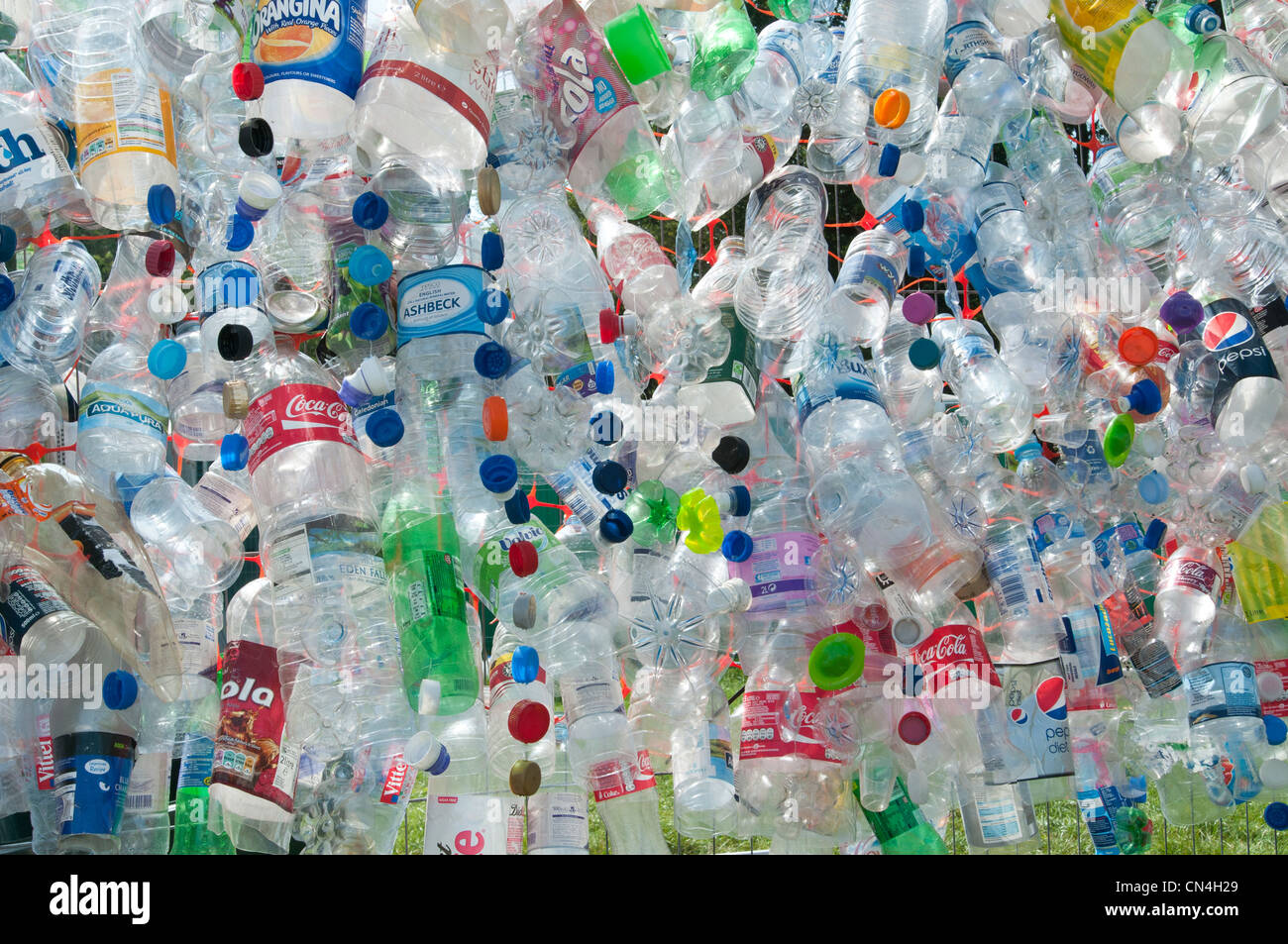 Discarded plastic bottles attached to a wire mesh fence highlight the need for more recycling of precious materials Stock Photo