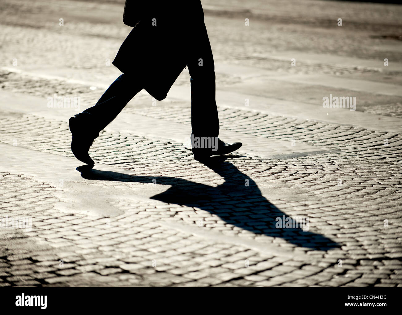 Legs of person walking on cobblestones Stock Photo