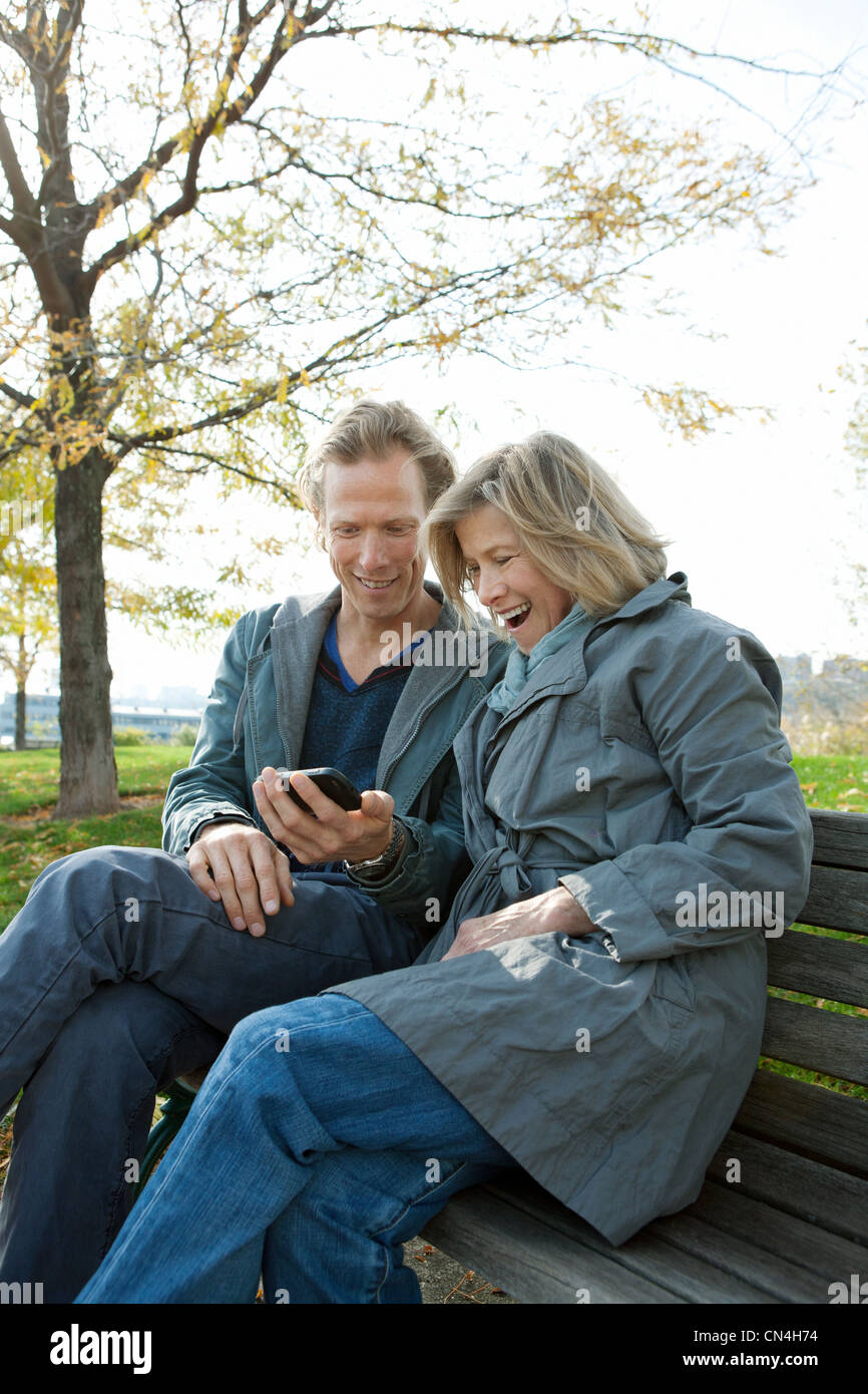 Mother and adult son on park bench looking at smartphone Stock Photo