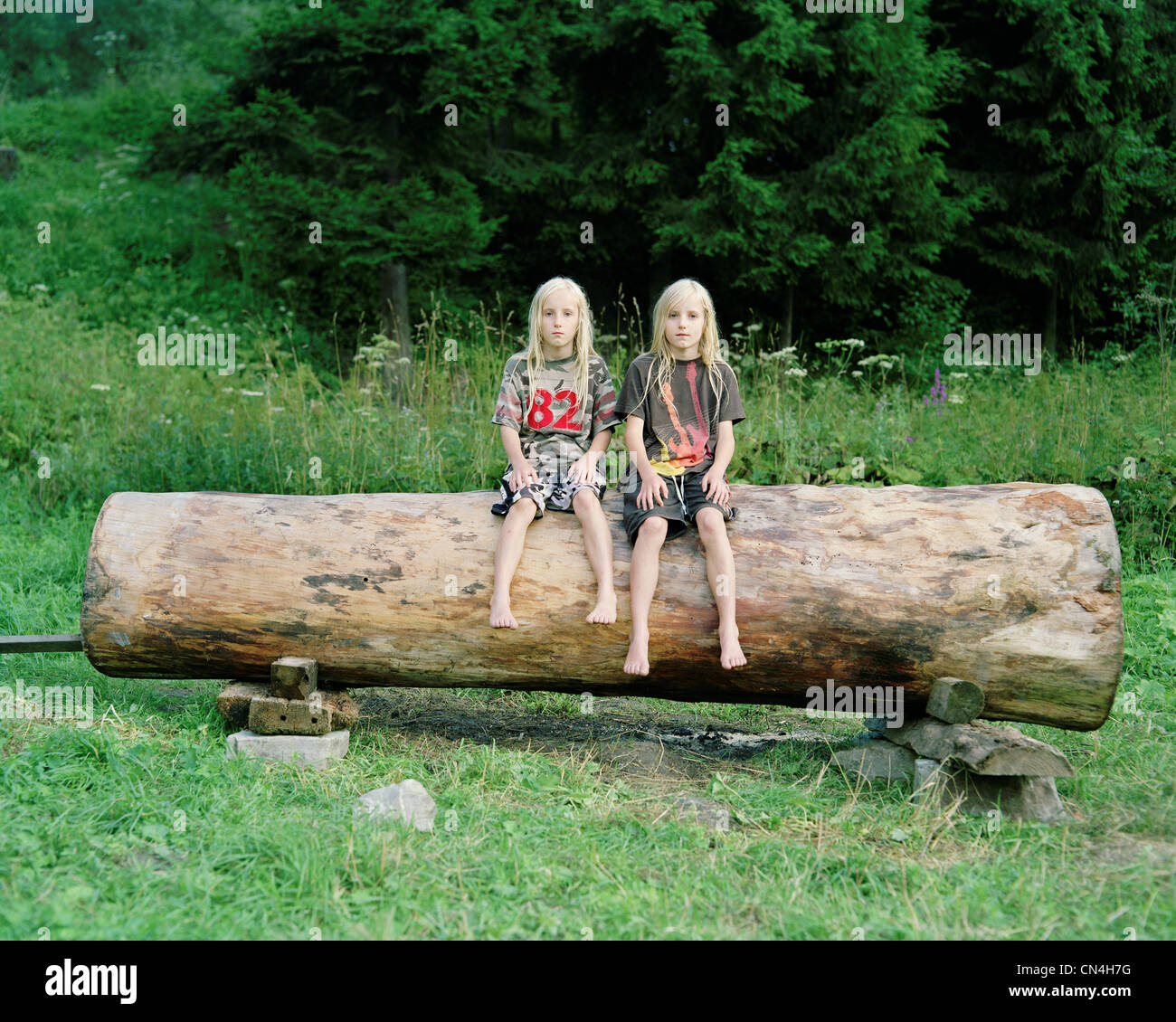 Twin brothers on a log, Nowica, Poland Stock Photo Alamy