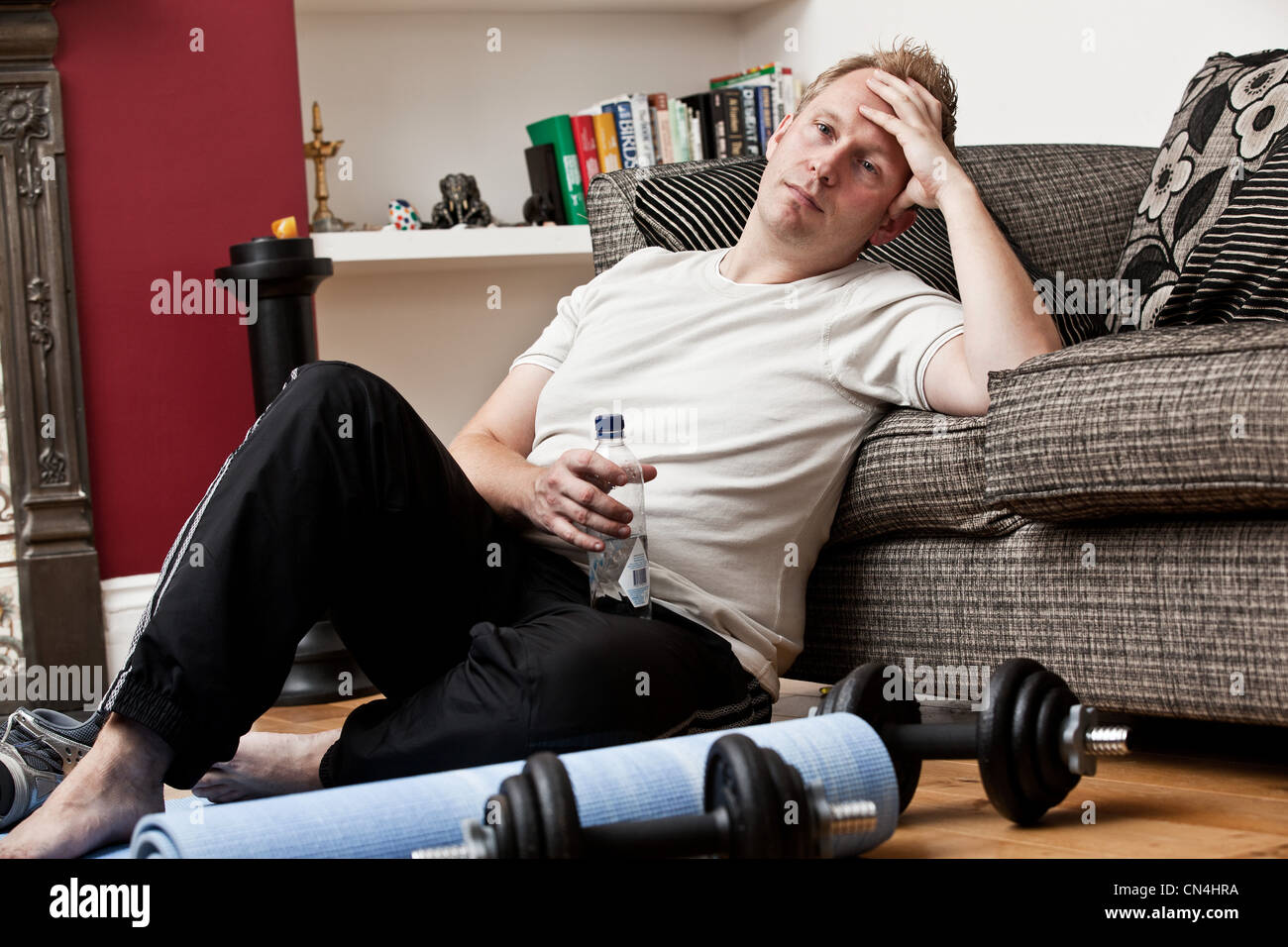 Mid Adult Man Leaning Against Sofa Resting From Exercise Stock